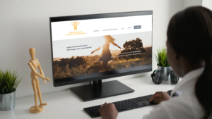 Das Bild zeigt den Ausschnitt einer Frau, die an einem PC sitzt. Auf dem Bildschirm ist die neue Website der Selbsthilfegruppe Endometriose Ortenaukreis zu sehen.